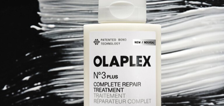 A bottle of OLAPLEX No.3PLUS Hair Repair treatment in front of a smear of the product