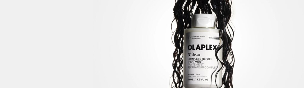Wet, curly dark hair hanging down and encompassing a No.3PLUS bottle