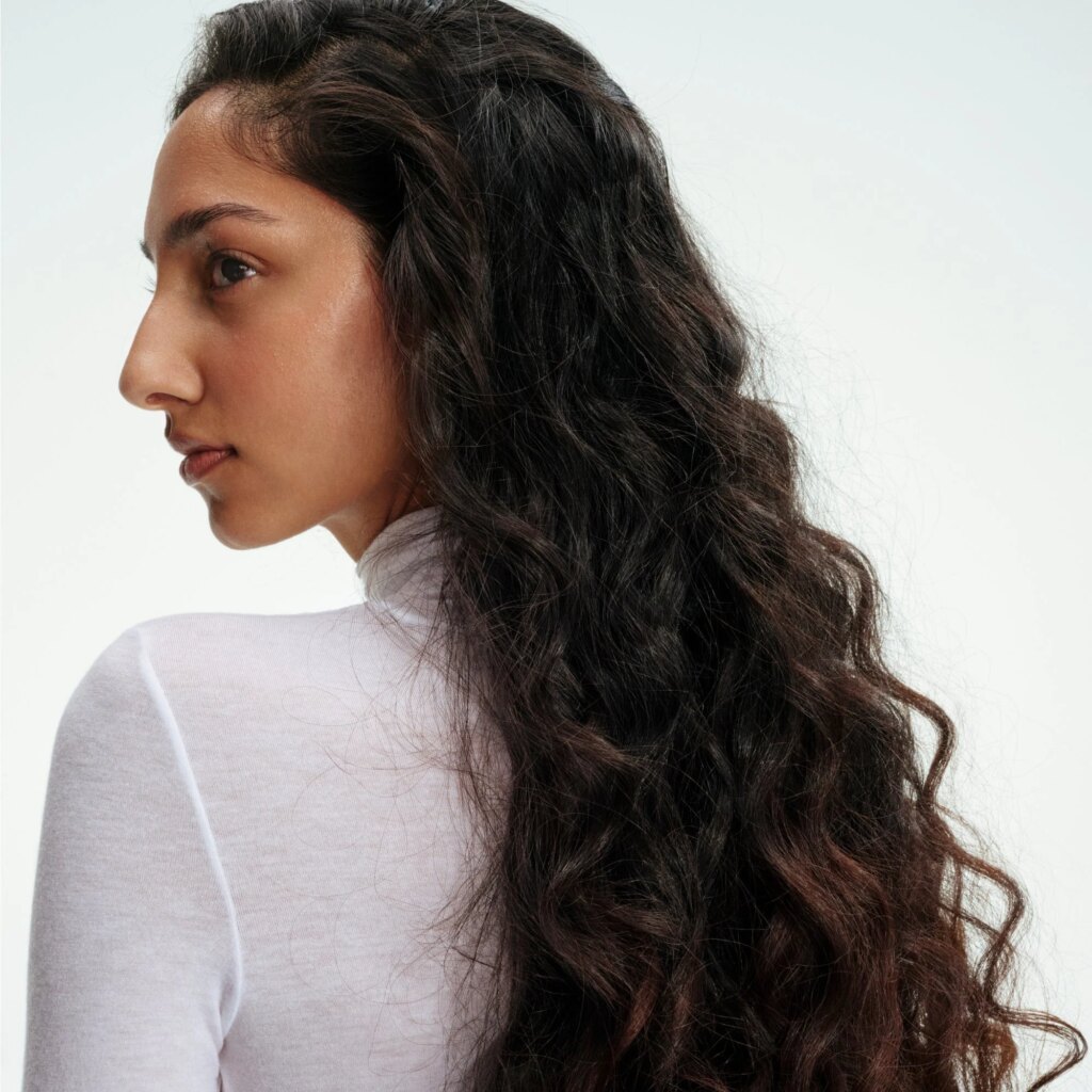 Woman with dark curly hair looking over her shoulder